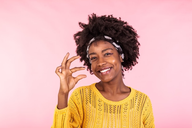 Mulher positiva, alegre, de pele escura e cacheada molda algo muito pouco com os dedos