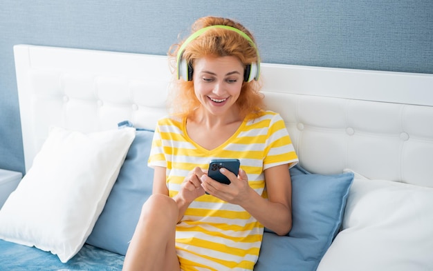 Mulher positiva em fones de ouvido ouve música no telefone mulher em casa ouve música em fones de ouvido