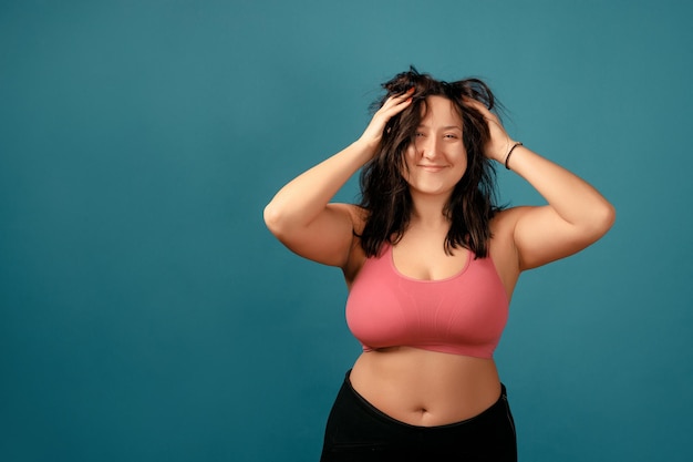 Foto mulher positiva feliz plus size. conceito positivo de corpo feliz. eu amo meu corpo. mulher atraente com excesso de peso posando na câmera no estúdio em um fundo colorido. a menina está vestindo um sutiã coral