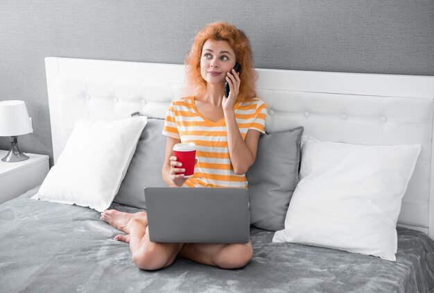 mulher positiva freelancer falando ao telefone freelancer mulher fala ao telefone mulher freelancer com laptop e café conversa ao telefone