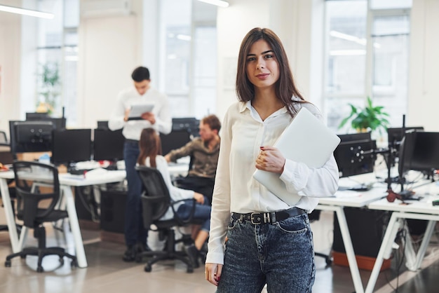 Mulher positiva na frente de jovens empresários que trabalham juntos no escritório moderno.