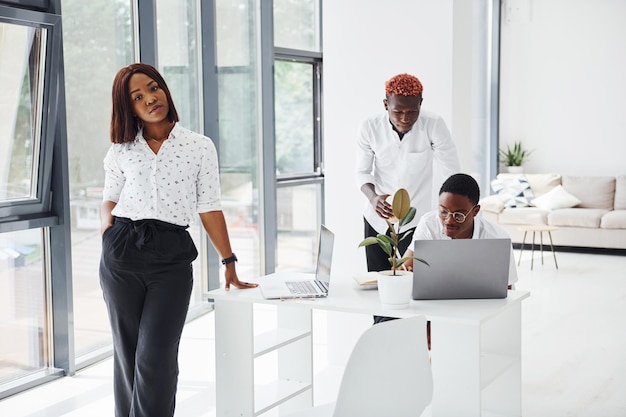 Mulher positiva posando para a câmera Grupo de empresários afro-americanos trabalhando juntos no escritório