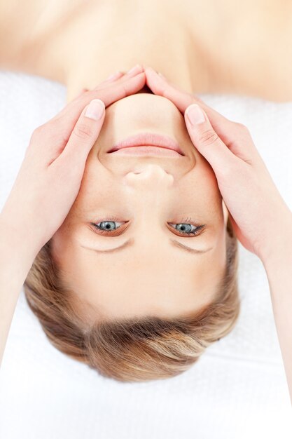 Mulher positiva recebendo uma massagem facial sorrindo para a câmera