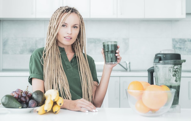 Mulher positiva segura xícara de suco verde fresco estilo de vida ecológico jovem bebendo suco verde em