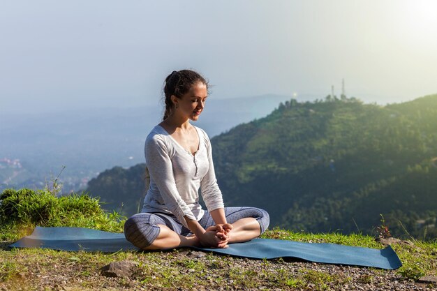 Mulher pratica ioga asana Baddha Konasana em pose de ângulo ao ar livre nas montanhas do Himalaia