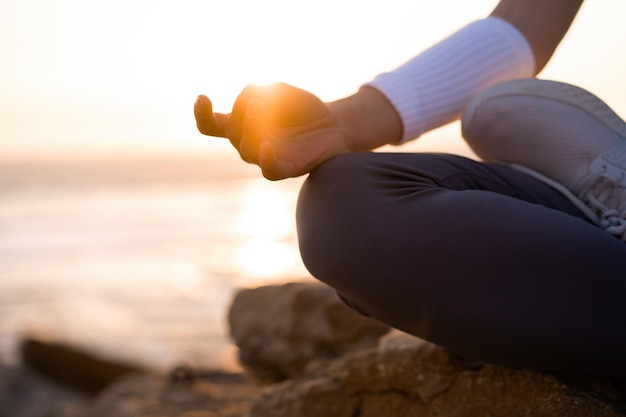 Mulher pratica ioga pose de lótus para meditação com férias de verão praia rochosa felicidade e relaxamento Exercício feminino calmo com ioga meditar praia oceânica com tempo dourado do pôr do sol