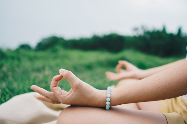 Mulher praticando aula de ioga, respiração, meditação, exercício, ao ar livre no campo de grama. bem estar, conceito de bem-estar