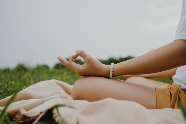 Mulher praticando aula de ioga, respiração, meditação, exercício, ao ar livre no campo de grama. Bem estar, conceito de bem-estar