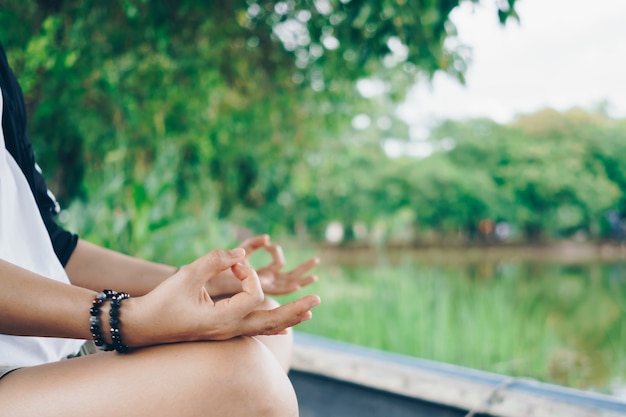 Mulher praticando aula de ioga, respiração, meditação, exercício, ao ar livre no campo de grama. Bem estar, conceito de bem-estar