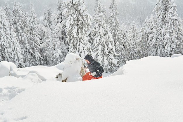 Mulher praticando caminhadas nas montanhas de inverno durante a queda de neve