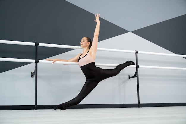 Mulher praticando divisão segurando corrimãos em estúdio de dança