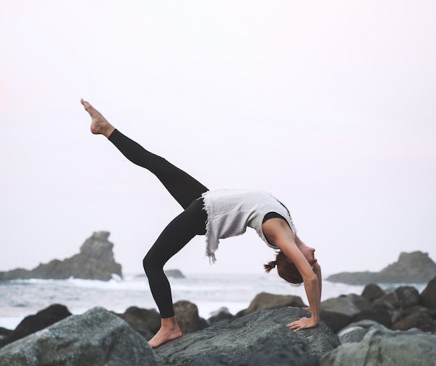 Mulher praticando ioga e meditação na bela praia selvagem