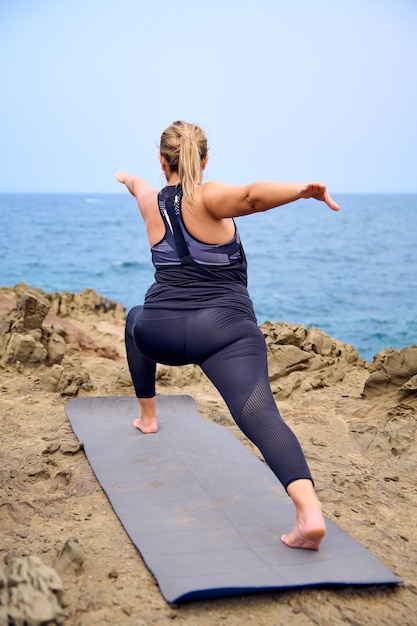 mulher praticando ioga em frente ao mar