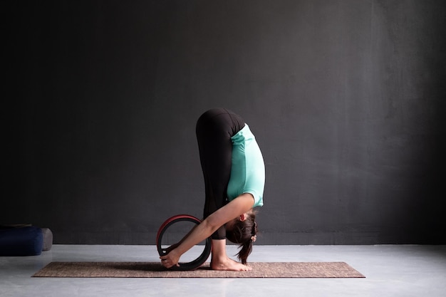 Mulher praticando ioga fazendo exercício de curvatura para a frente usando a pose de uttanasana de roda