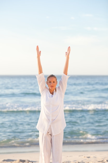 Mulher praticando yoga na praia