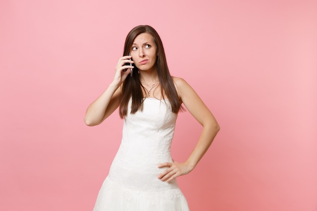 Mulher preocupada em um vestido branco olhando para cima e falando no celular