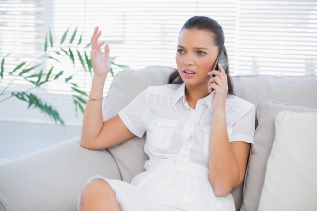 Mulher preocupada em vestido branco tendo um telefonema