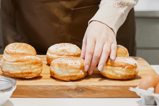 Mulher prepara rosquinhas frescas com geleia na cozinha de casa Cozinhando tradicional sufganiyot judaico de Hanukkah