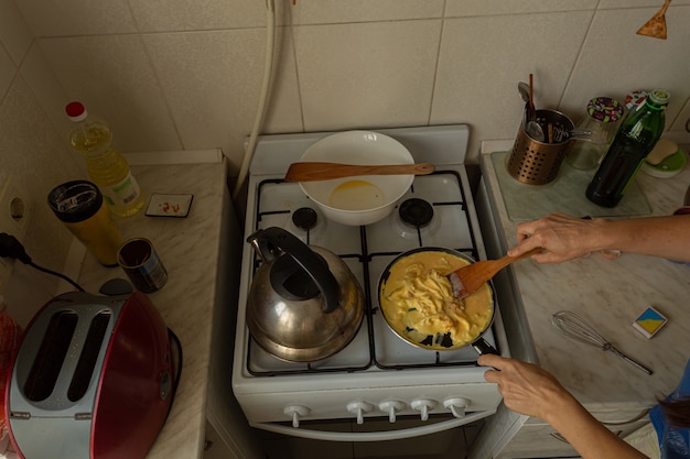 Mulher prepara uma omelete no fogão a gás.