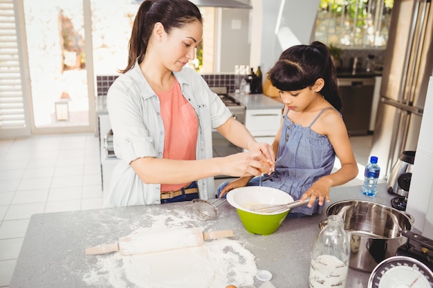 Mulher preparando comida com a filha em casa