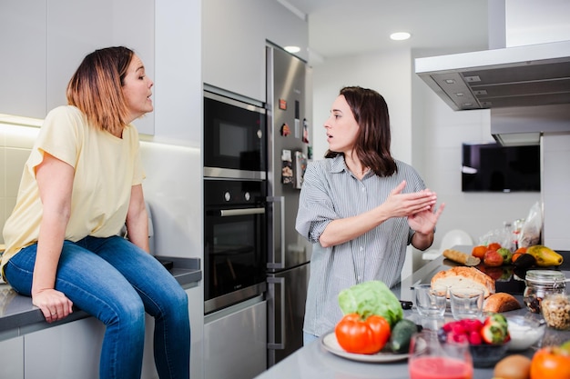 Mulher preparando comida enquanto está de pé com um amigo na cozinha