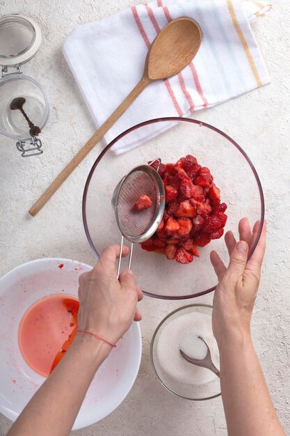 Mulher preparando geléia de morango em sua cozinha em casa vista superior