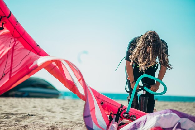 Mulher preparando pipa de kitesurf com a bomba de ar