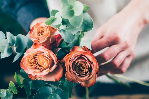 Mulher preparando um buquê de rosas vermelhas