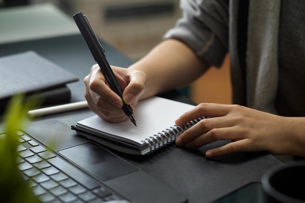 Foto mulher presta atenção ao fazer anotações no bloco de notas na mesa do escritório.