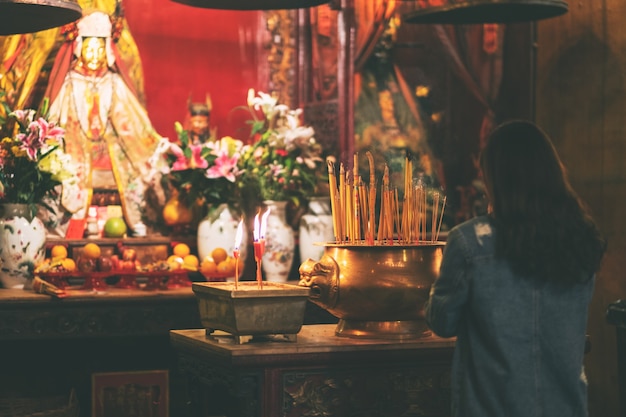 Mulher prestando homenagem à imagem de Buda em templo chinês