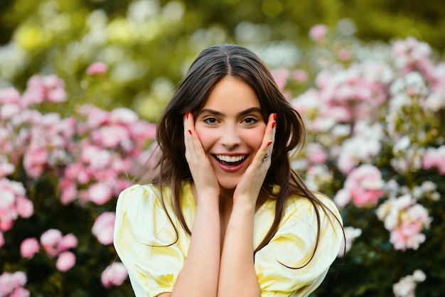 Mulher primavera sorrindo no jardim de rosas ao ar livre Garota de beleza natural aproveita a recreação de verão