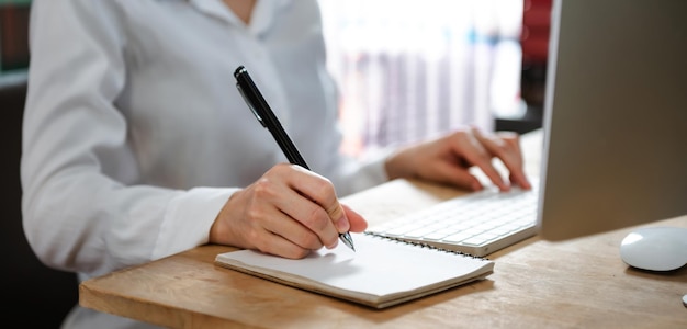 Mulher profissional escrevendo seus conceitos de ideia no notebook enquanto trabalhava em seu projeto