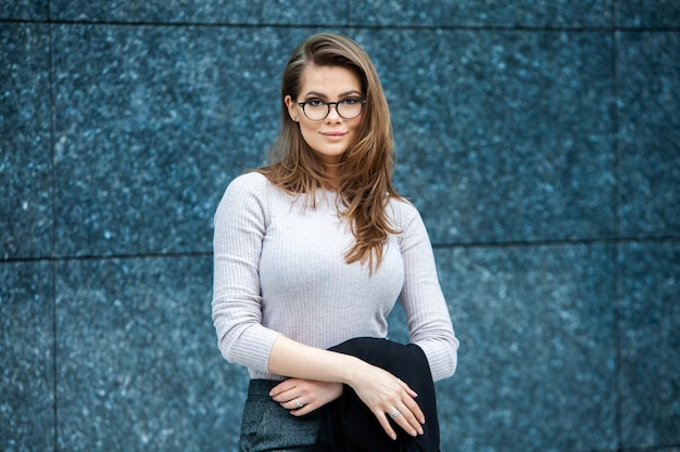 Mulher profissional feliz e bem-sucedida posando perto de um prédio comercial