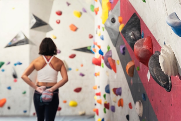 Mulher pronta para praticar escalada em parede artificial dentro de casa. Estilo de vida ativo e conceito de boulder.