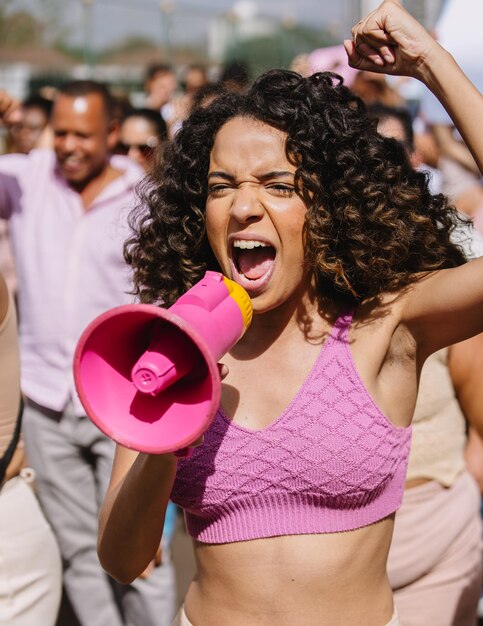 Mulher protestando com um megafone no meio da multidão Foto vertical