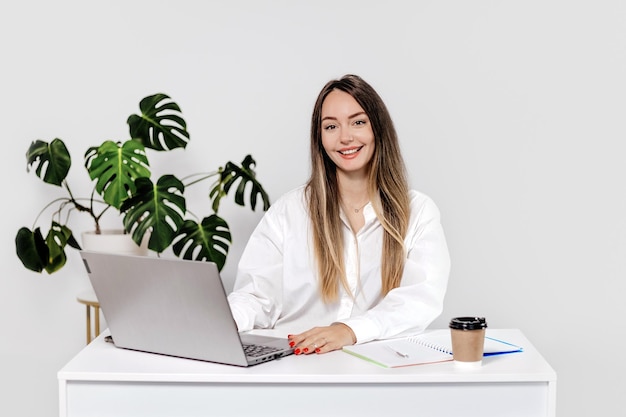 mulher psicóloga sentada em uma mesa com um laptop sorrindo isolada em um fundo branco