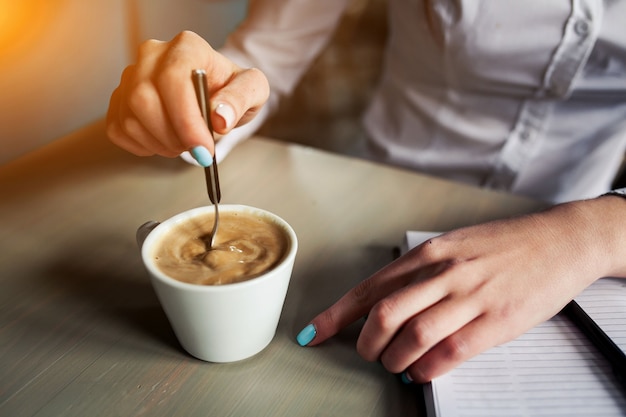 Mulher que agita o café com uma colher de chá