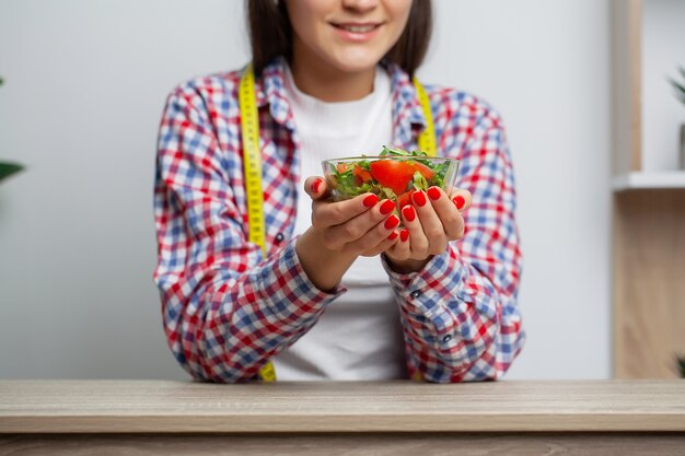 Mulher que come a salada da dieta para a perda de peso.