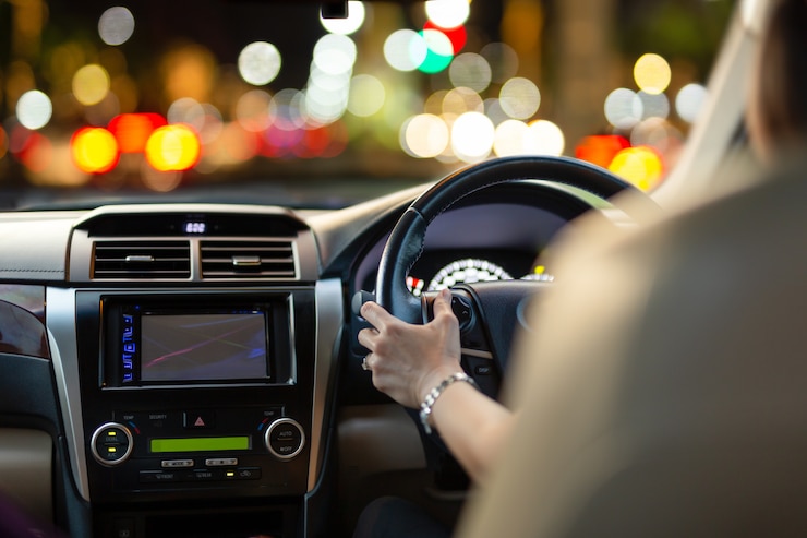 Foto mulher que conduz um carro com luzes do bokeh do engarrafamento no nighttime.