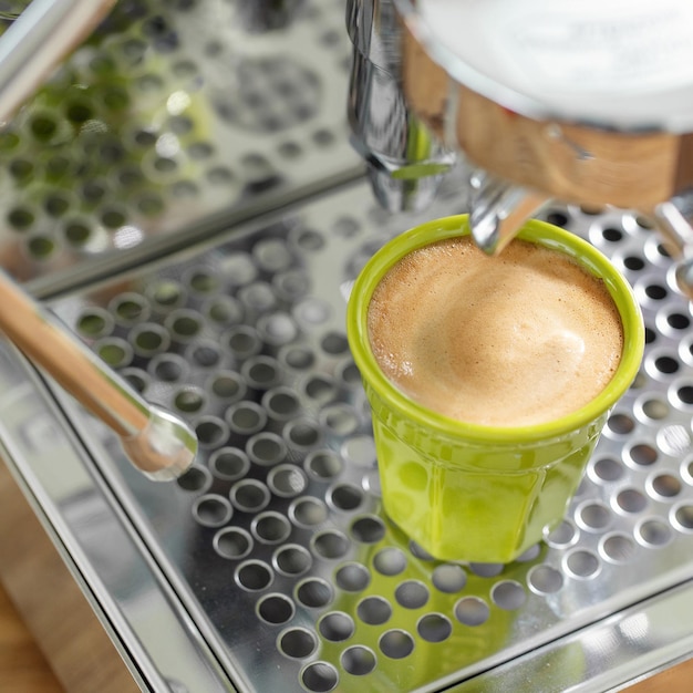 Mulher que cozinha o café expresso com a máquina