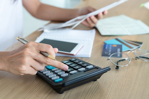 Foto mulher que guarda contas e que usa o calcutor, a conta e o conceito da economia.