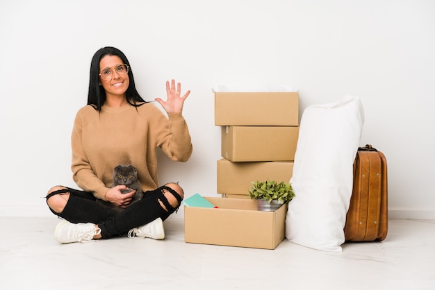 Mulher que move-se para casa no branco que mostra alegre número cinco de sorriso com dedos.