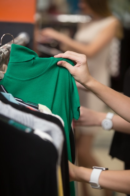 Mulher que olha uma camisa verde