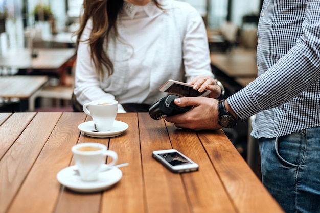 Mulher que paga com telefone celular no restaurante do café.