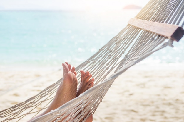 Mulher que relaxa na rede na praia