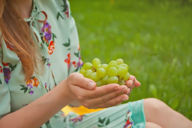 Mulher que senta-se na tampa amarela e que guarda o grupo de uvas.