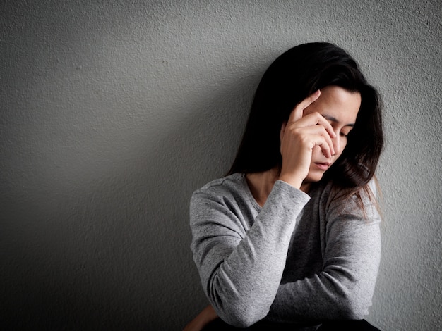 Mulher que senta-se sozinho no quarto escuro em casa. conceito solitário, triste.