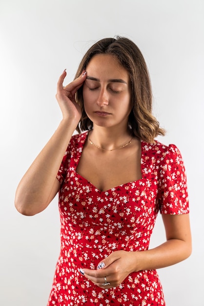 Mulher que sofre de dor de cabeça, segurando as mãos atrás da cabeça, isolada em um fundo branco