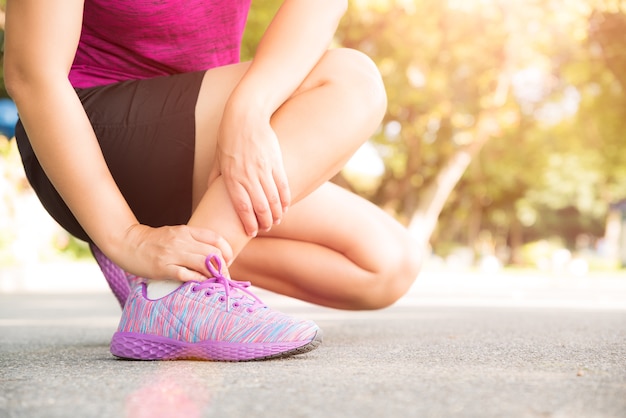 Mulher que sofre de uma lesão no tornozelo durante o exercício.