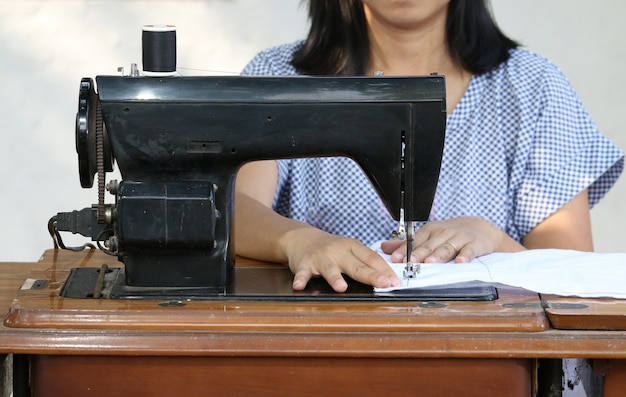 Mulher que trabalha com a máquina de costura.